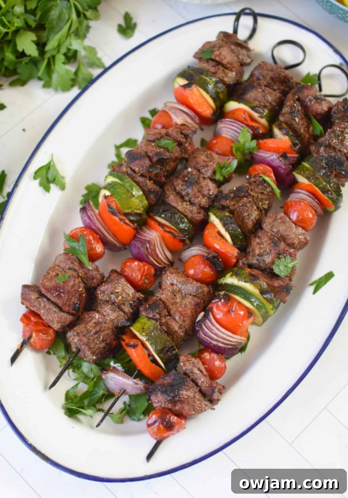 Authentic Greek Beef Souvlaki 2 Beef Souvlaki on a white platter, garnished with fresh herbs