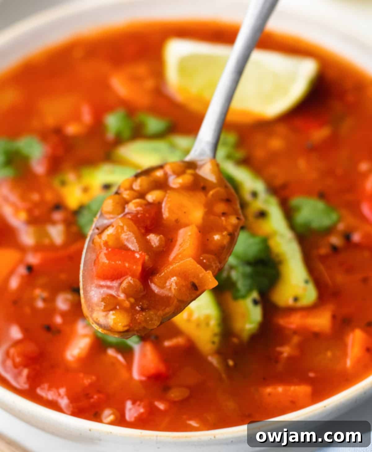 Mexican Lentil Soup 3 A close-up shot of Mexican Lentil Soup in a white bowl with a spoon, highlighting its texture.