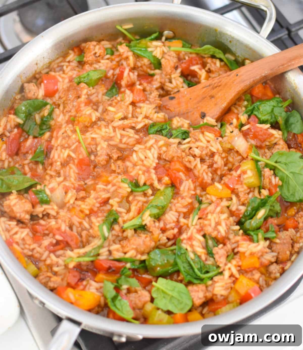 Creamy Cajun Sausage and Rice Skillet 8 Spinach being stirred into Creamy Cajun Sausage Rice Skillet