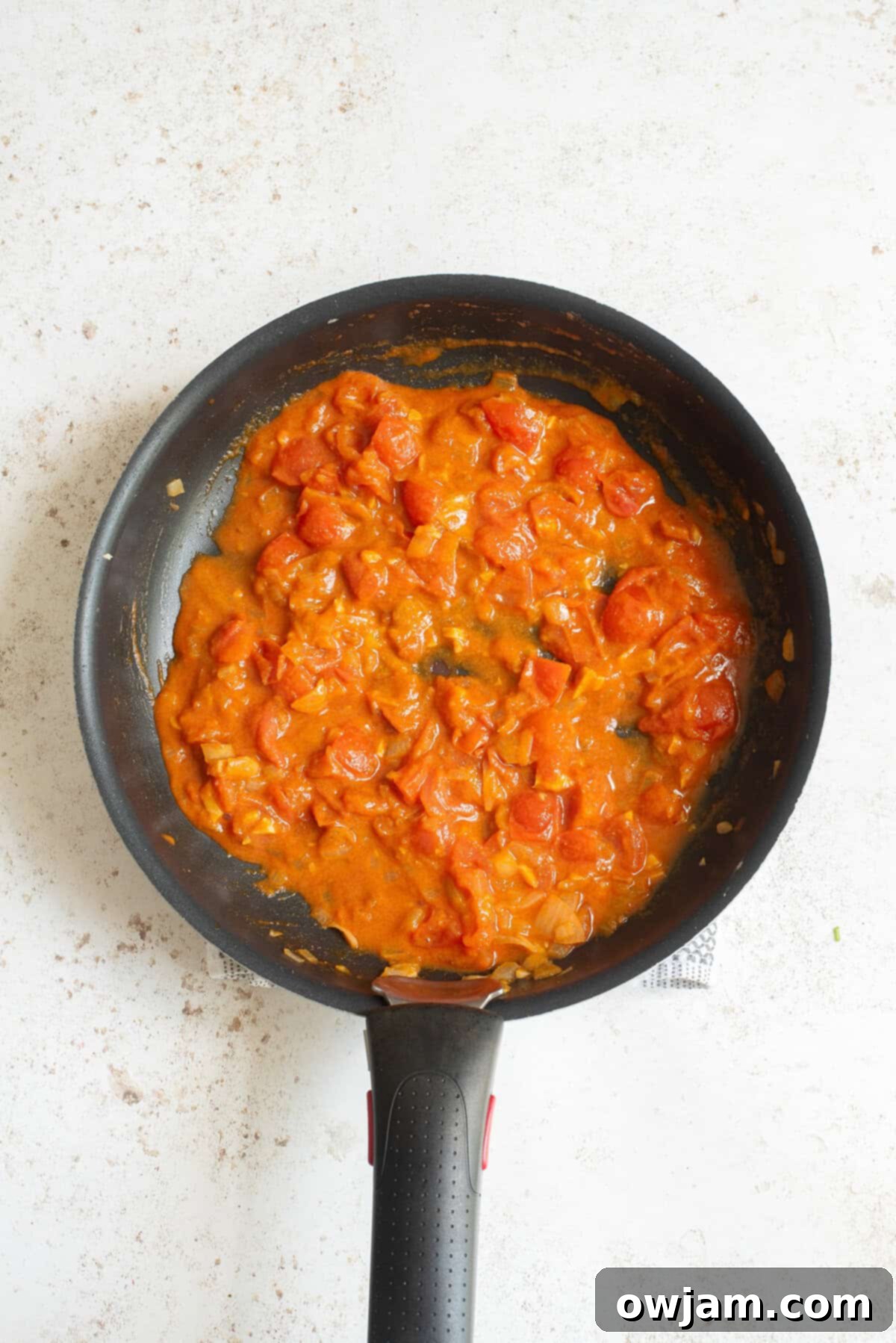 Cozy Sweet Potato Lentil Curry 6 Onions, garlic, and tomatoes sautéing in a skillet, forming the base of the Sweet Potato Lentil Curry.