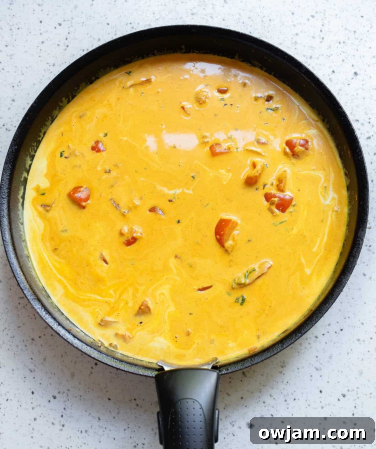 Luscious Coconut Fish Curry 8 The creamy coconut curry sauce simmering in a black skillet, perfectly infused with spices.
