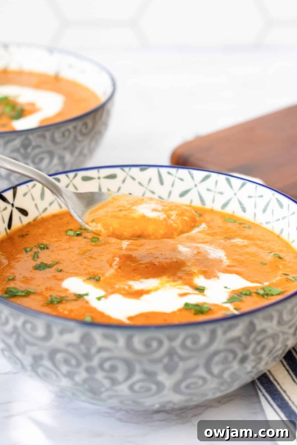 Spiced Tomato & Lentil Delight 2 A comforting bowl of Lentil Tomato Soup with a spoon, garnished with fresh herbs and a swirl of cream.