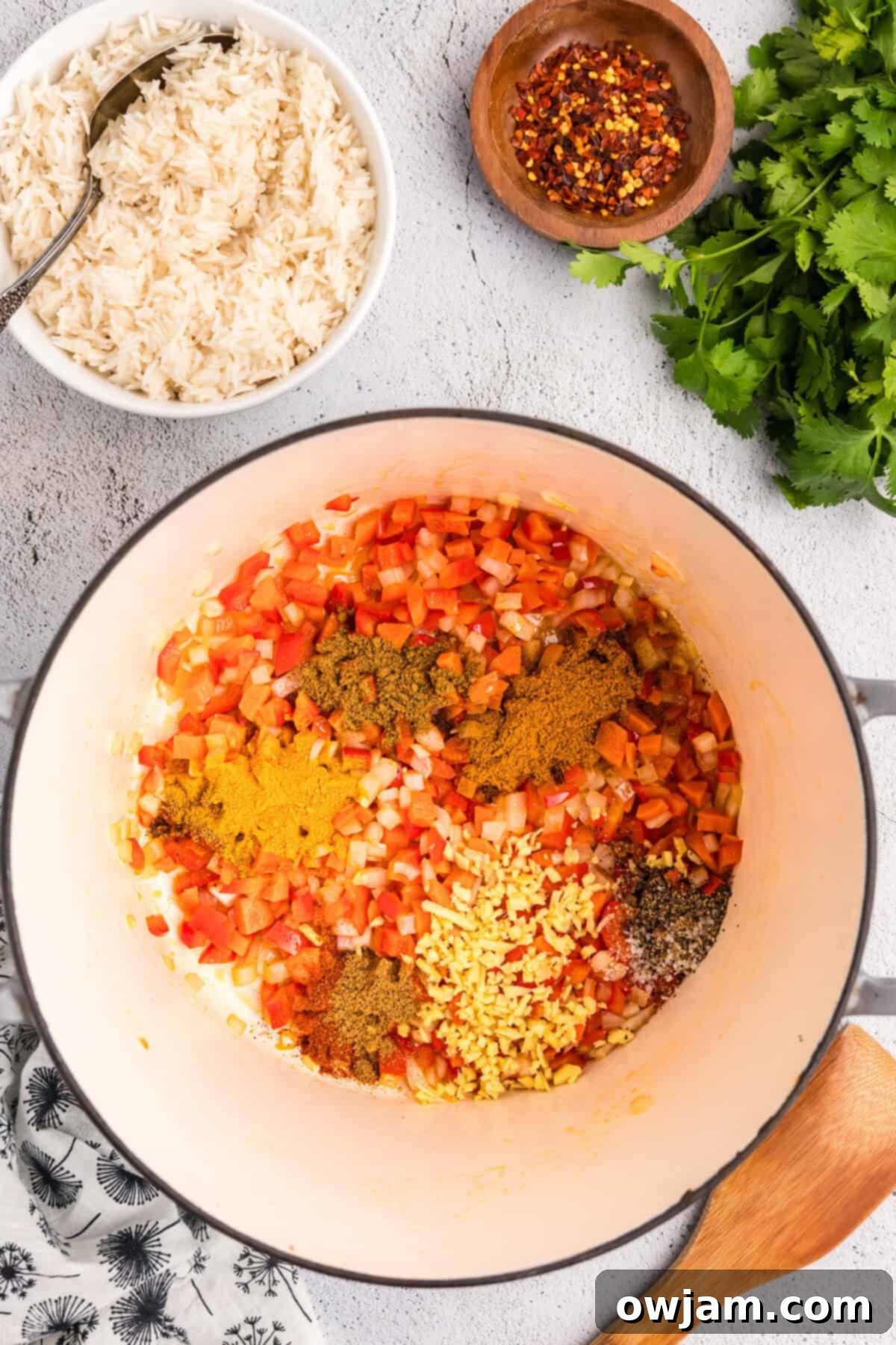 Simple Satisfying Red Lentil Dahl 7 A mix of aromatic spices and tomato paste being stirred into sautéed vegetables in a large pot
