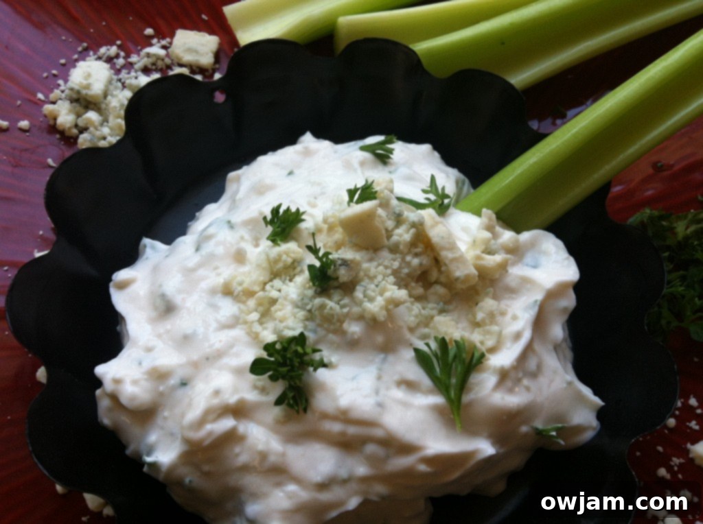 A bowl of healthy buffalo dip surrounded by an assortment of fresh vegetables and chips for dipping.