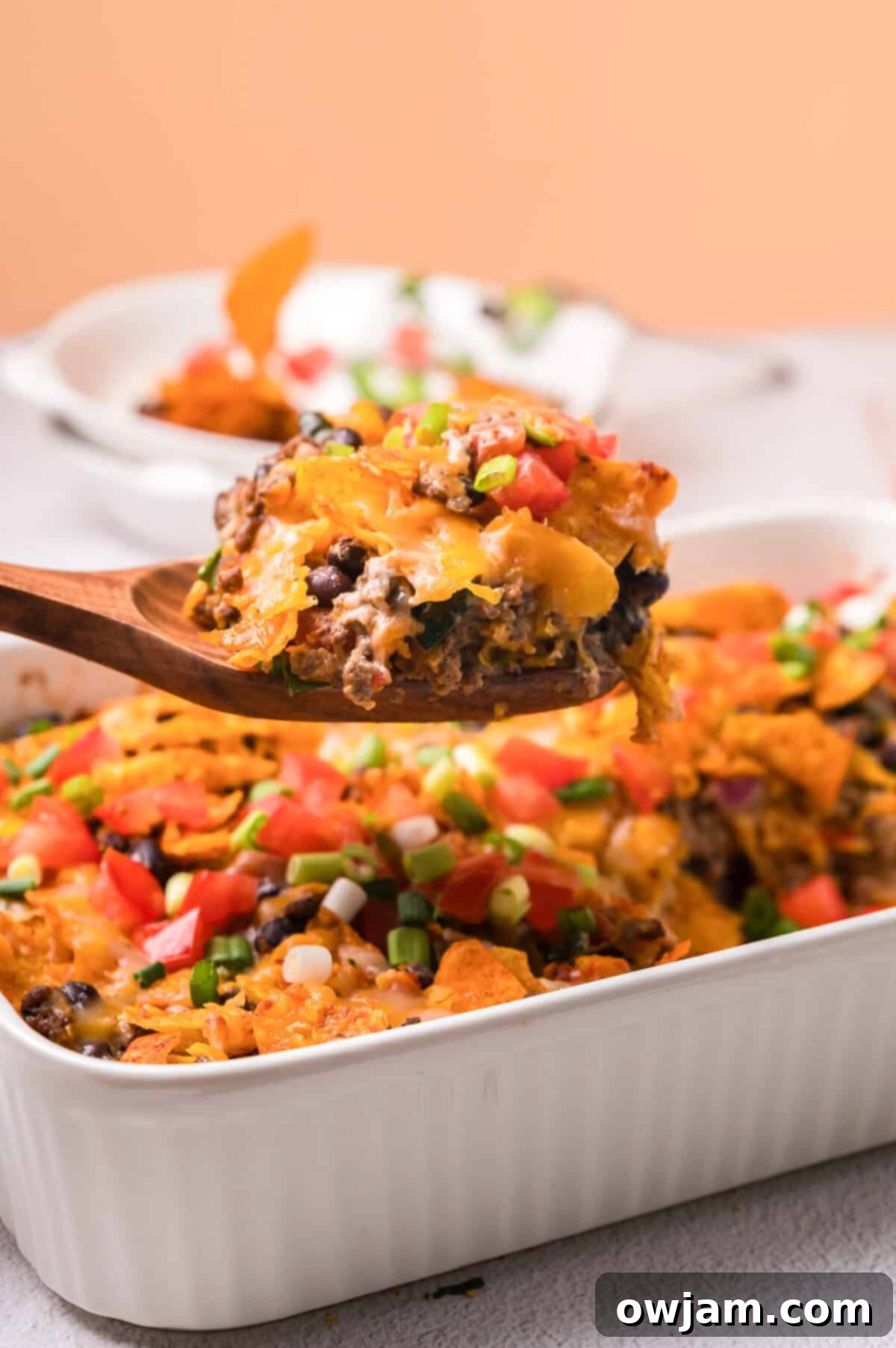 A delicious Doritos Taco Casserole in a baking dish, ready to be served, topped with melted cheese and crushed Doritos.