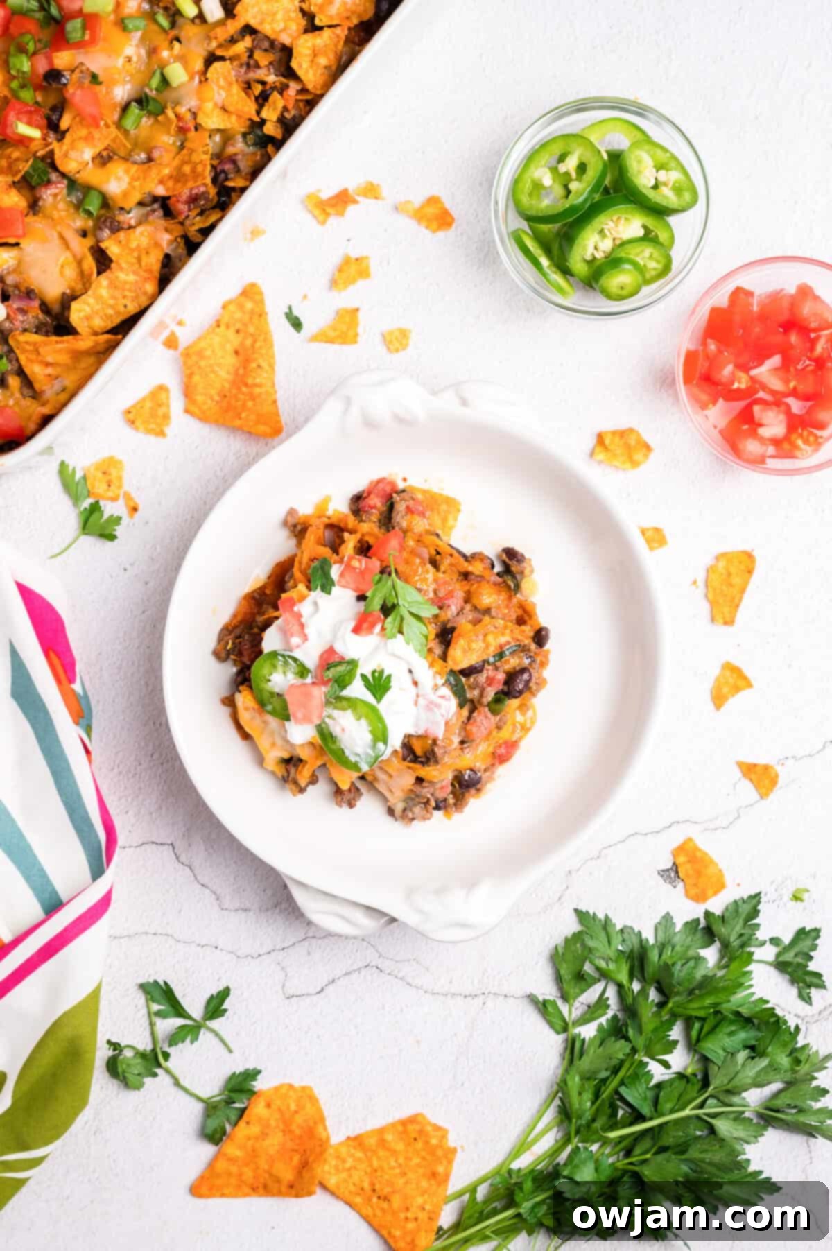A plate of Doritos Taco Casserole garnished with fresh cilantro and a lime wedge.