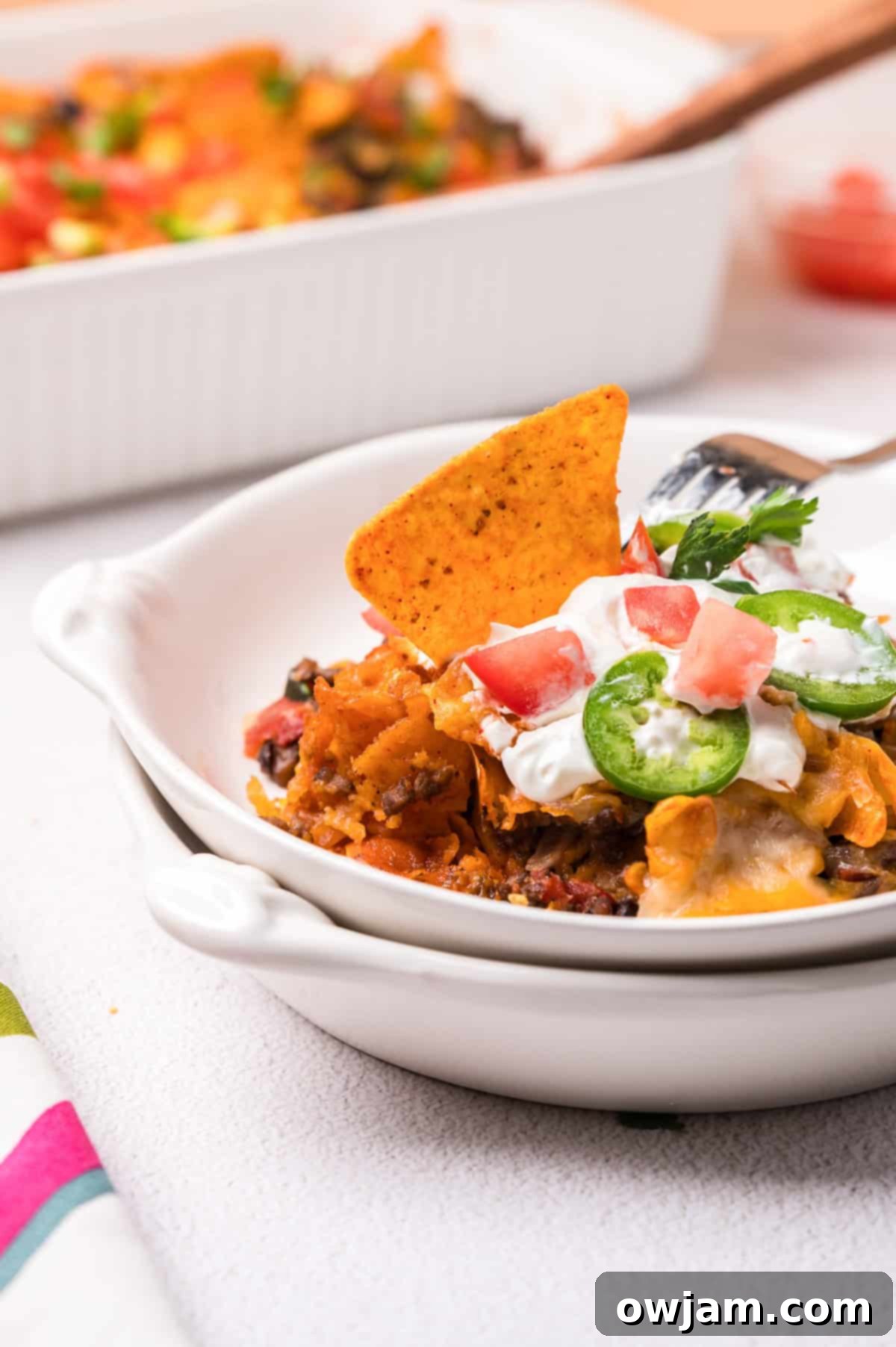 A serving of Doritos Taco Casserole in a white bowl, garnished with fresh cilantro, showing the crunchy chip topping.