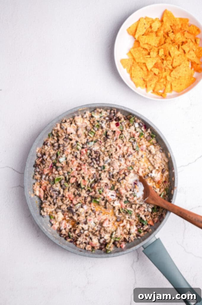 Cooked ground beef and vegetables combined in a skillet, forming the base of the casserole.