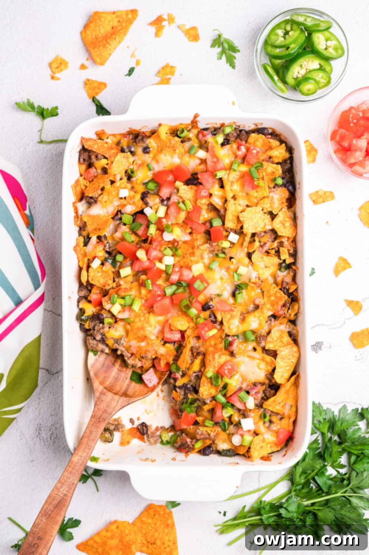 A serving spoon lifting a scoop of Doritos Taco Casserole from the dish.