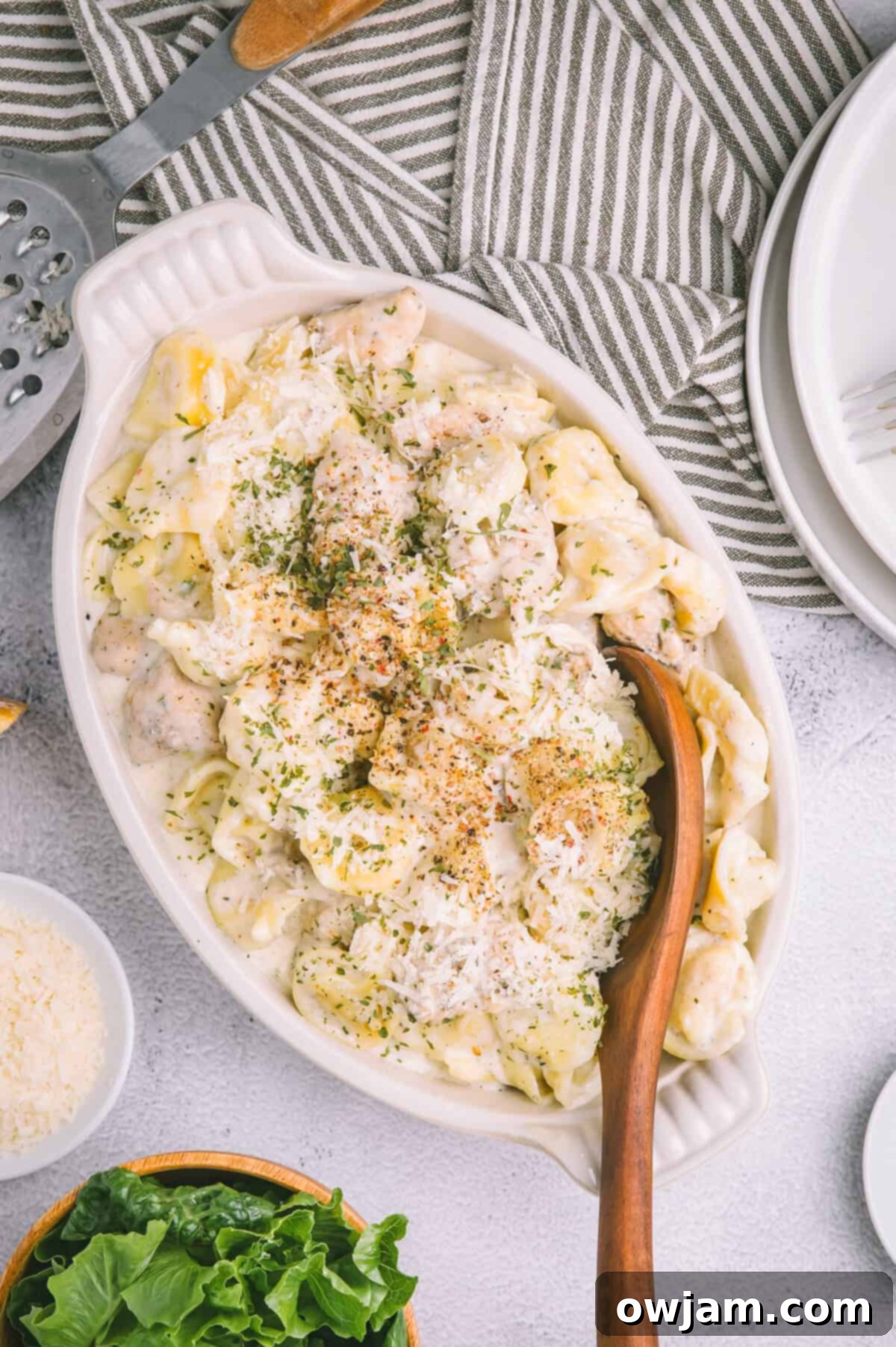 A close-up of Olive Garden Chicken Tortellini Alfredo with a serving spoon, highlighting the creamy texture.