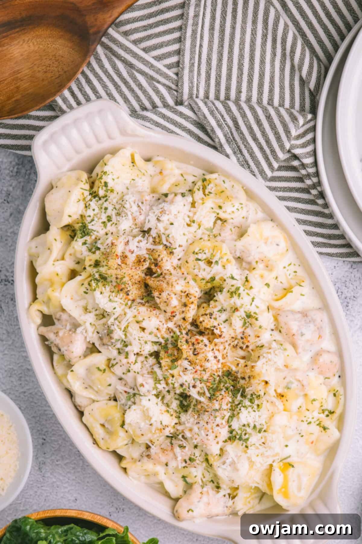 Olive Garden Chicken Tortellini Alfredo baking in a white dish, topped with golden breadcrumbs.