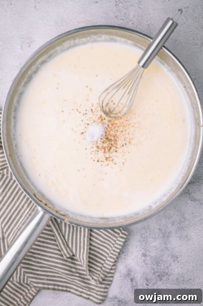 Creamy Alfredo sauce simmering in a skillet, capturing its rich texture.