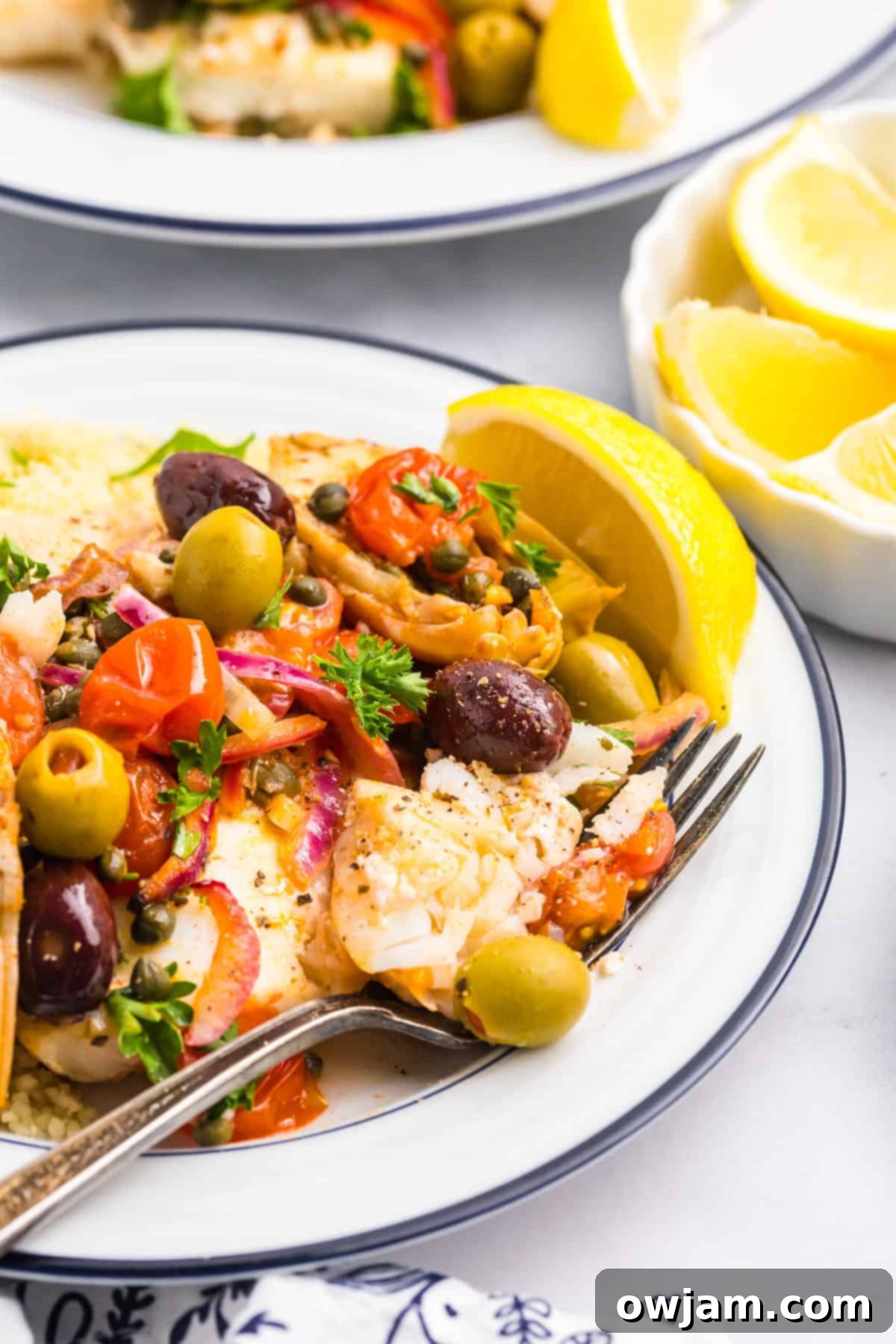 Sun-Kissed Mediterranean Fish Bake 2 Mediterranean Baked Fish on a white plate with fork