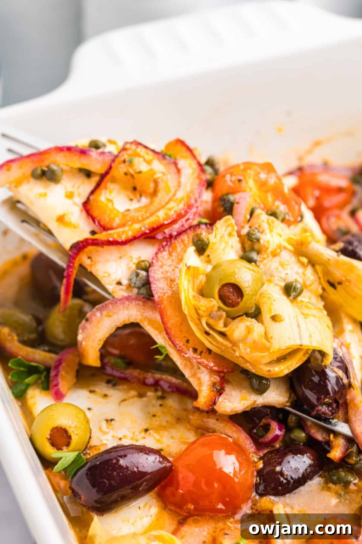 Sun-Kissed Mediterranean Fish Bake 3 Mediterranean Baked Fish in a baking dish with a serving spoon