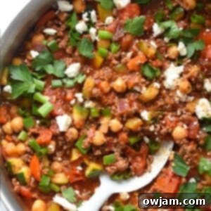 Overhead view of Mediterranean Ground Beef Skillet in a pan, topped with feta and fresh herbs