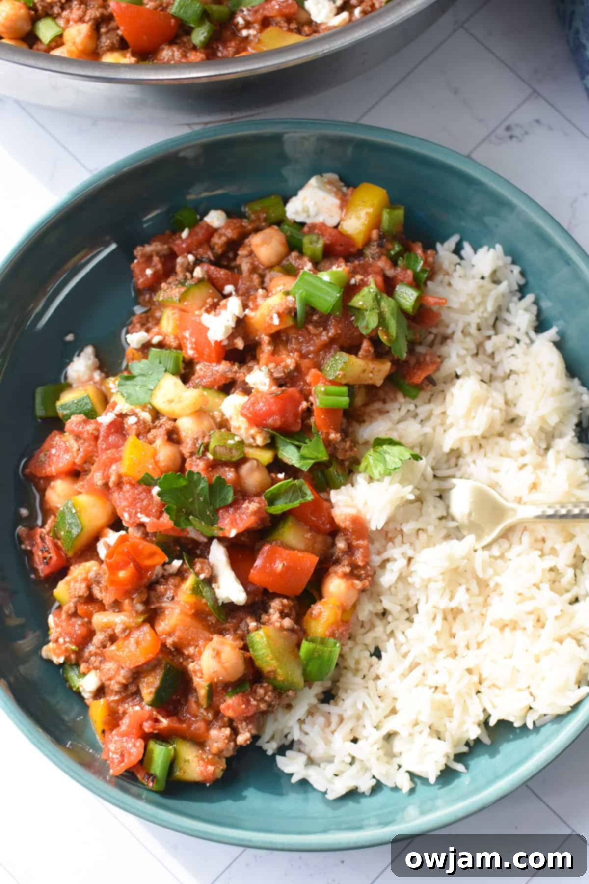Mediterranean Ground Beef Skillet served in a bowl with a fork, showing the vibrant mix of beef, vegetables, and feta