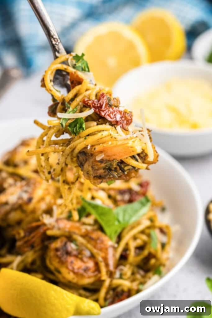 A fork twirling strands of Shrimp Pesto Pasta, showcasing the sauce and shrimp