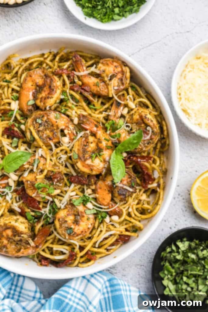A close-up of Shrimp Pesto Pasta in a pan, topped with fresh basil leaves
