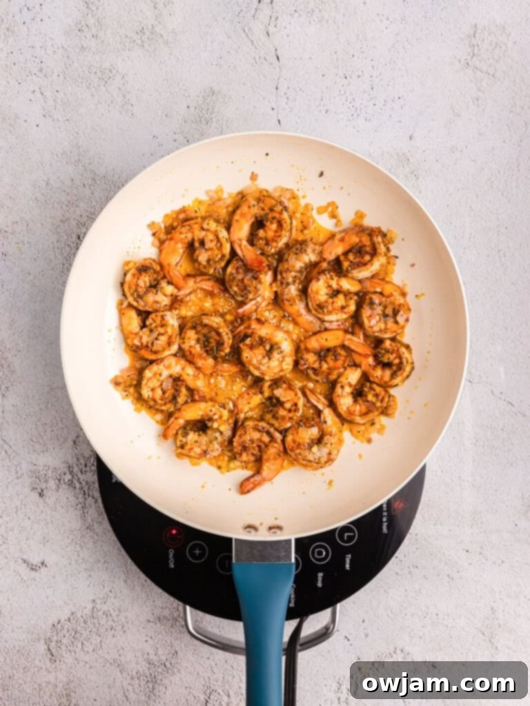 Shrimp cooking in a skillet with garlic and shallots