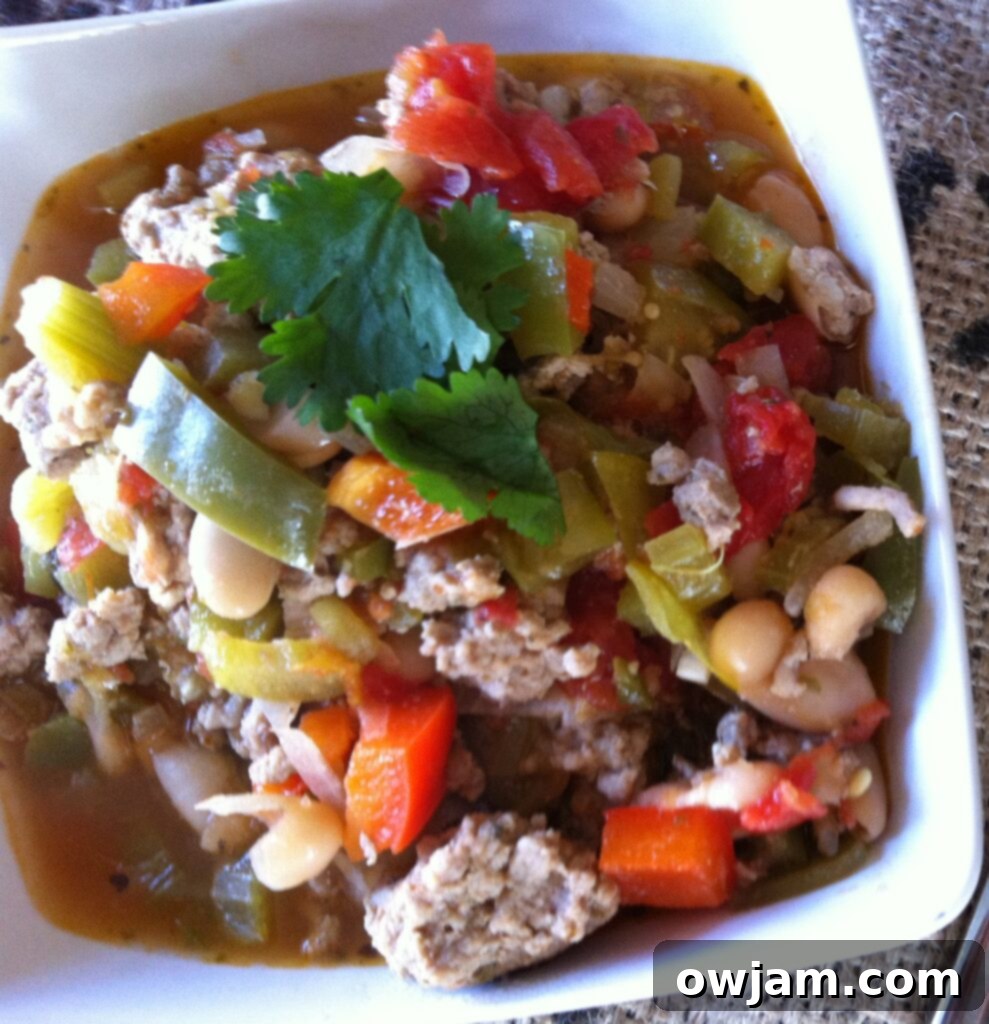 A close-up of a generously filled bowl of spicy Cajun Green Chili, garnished and ready to eat