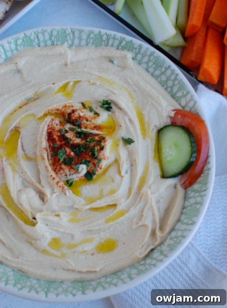 Master the Art of Lebanese Hummus 5 Lebanese Hummus Recipe served in a teal bowl, garnished with herbs and a drizzle of olive oil