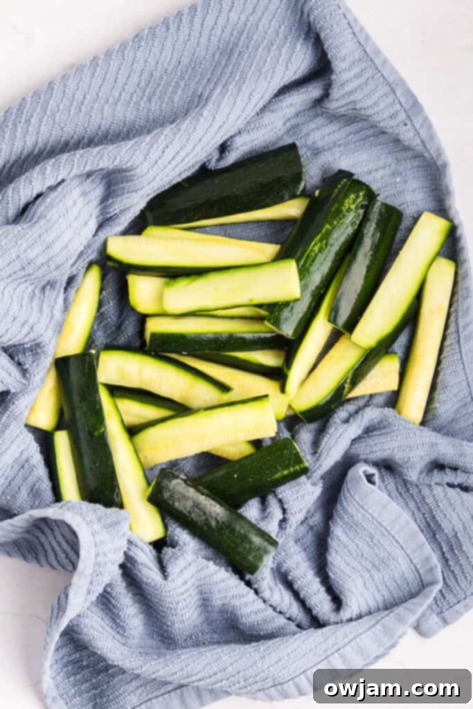 Crispy Air Fryer Zucchini Sticks 11 Close-up of zucchini sticks in a colander, salted to draw out moisture.