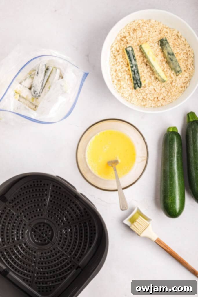 Crispy Air Fryer Zucchini Sticks 13 Zucchini sticks being coated in the breadcrumb mixture using a fork.