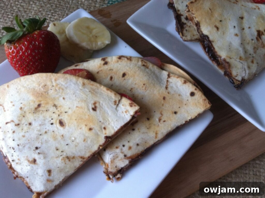 Close-up of a Dessert Quesadilla garnished with fresh fruit and a drizzle of chocolate syrup.