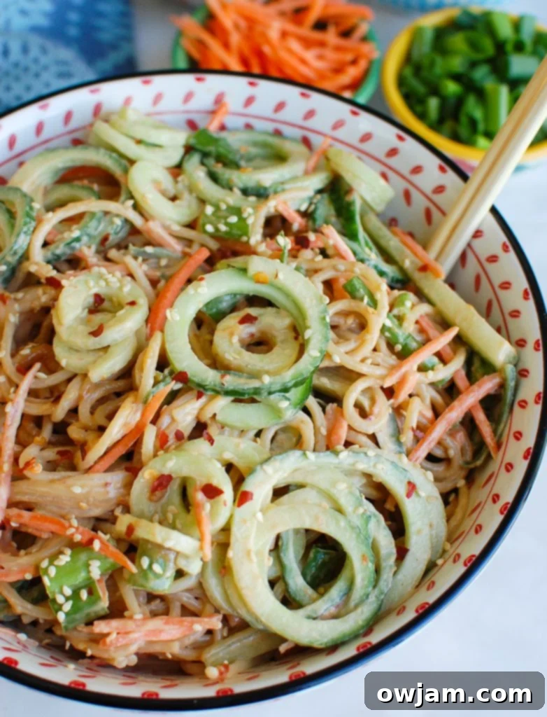 Vibrant Sesame Noodles with Chopsticks, showcasing fresh vegetables and a rich peanut sauce, ready to be enjoyed.