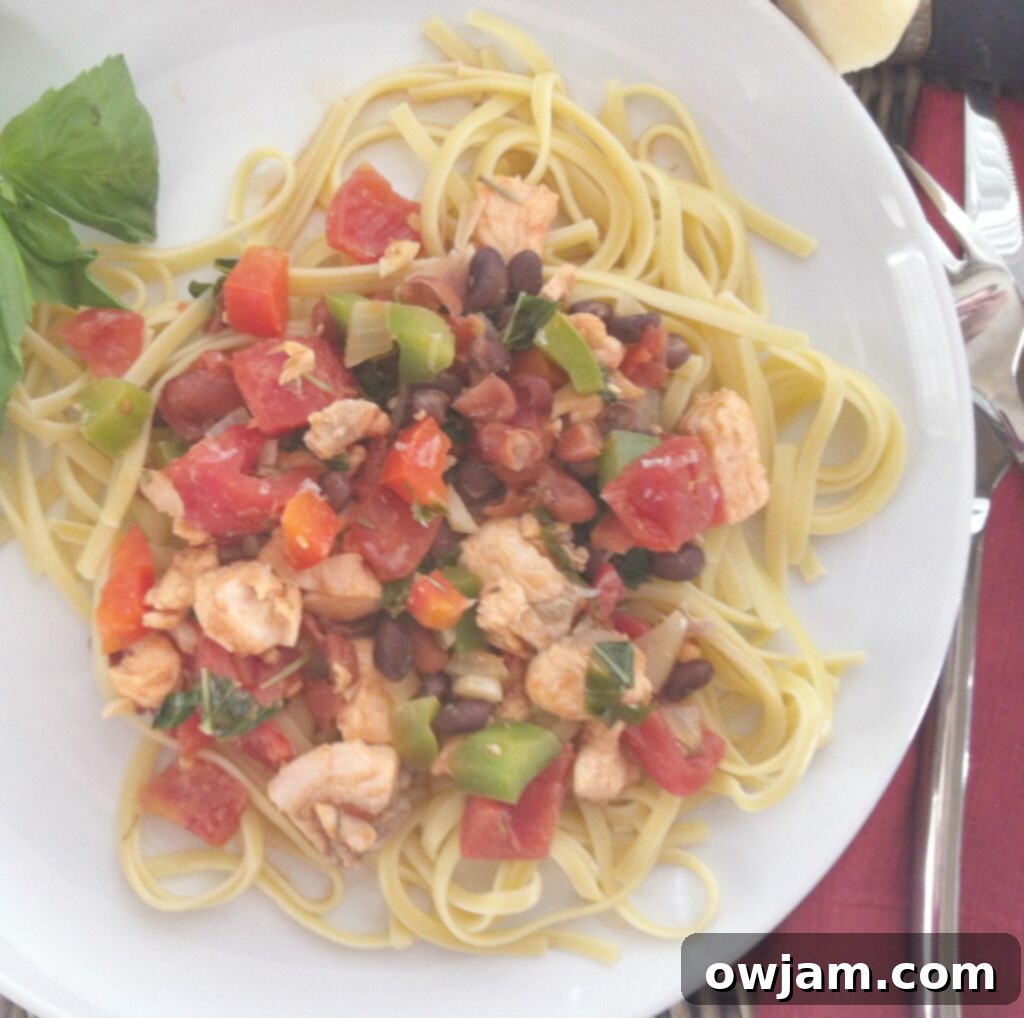 Large serving bowl of Salmon Linguine garnished with freshly grated Parmesan cheese and a sprig of basil, glistening under warm light.