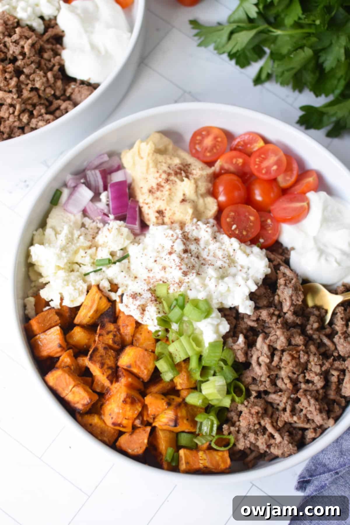 Hearty Sweet Potato Cottage Cheese Ground Beef Bowls 2 Sweet Potato Cottage Cheese Bowls with a gold fork in a white bowl.