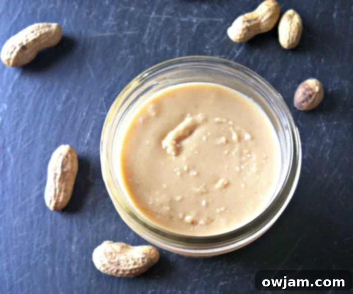 Delicious Homemade Peanut Butter Recipe, with a spoon scooping out the rich, creamy spread from a jar.