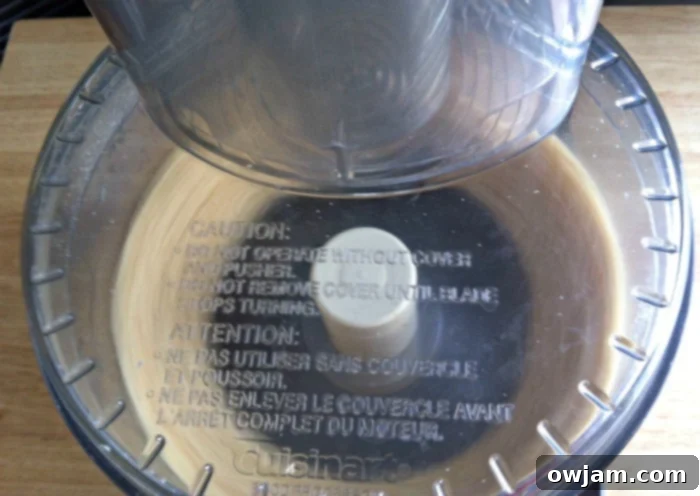 Peanuts transforming into a coarse peanut butter texture in a food processor.