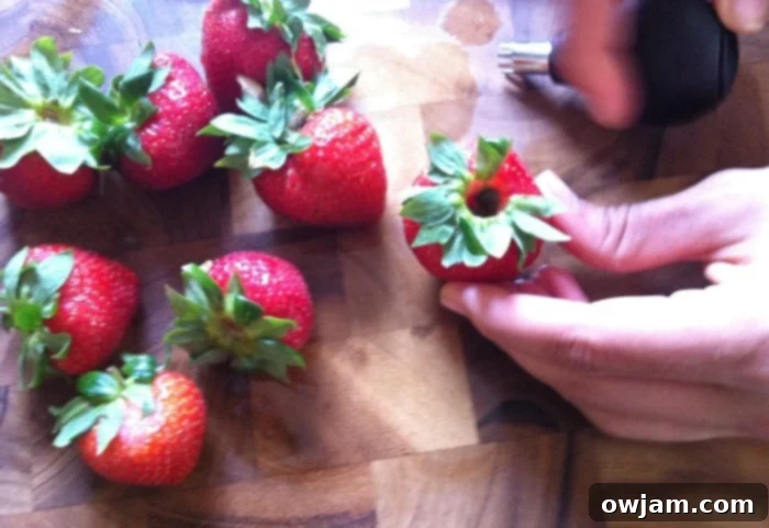 Fresh, ripe strawberries, perfectly hulled and ready for slicing, showcasing the effectiveness of the huller.