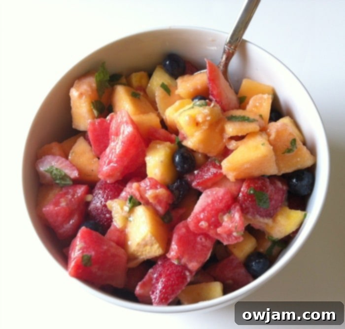 A large, inviting bowl filled with a colorful fruit salad, glistening with the creamy yogurt honey lemon dressing.