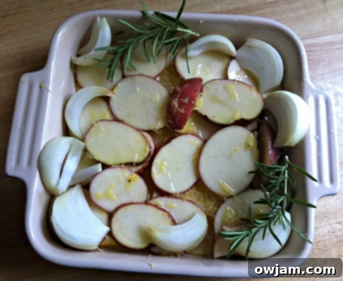 Preparation of Lemon Rosemary Chicken and Red Potatoes, seasoned and ready to roast on a baking sheet