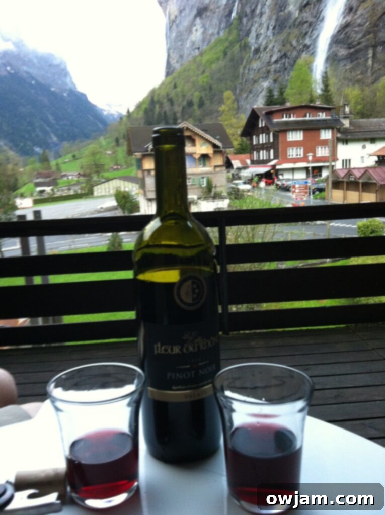 A person relaxing on a balcony with a glass of wine, overlooking the beautiful alpine scenery in Interlaken, Switzerland.
