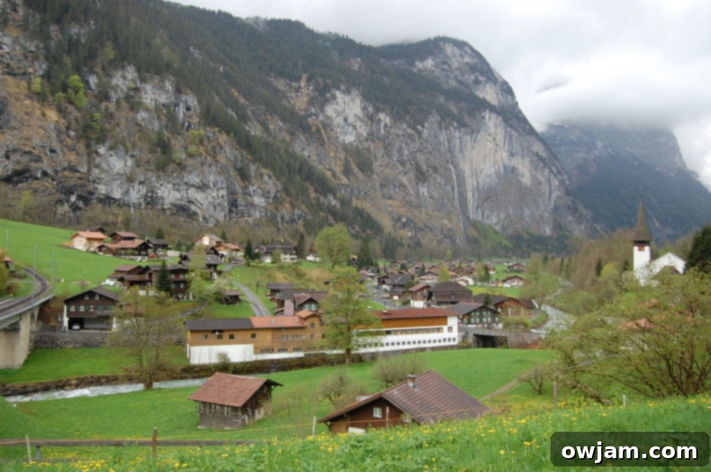 Expansive view of the verdant countryside in Lauterbrunnen, with traditional buildings and mountains.