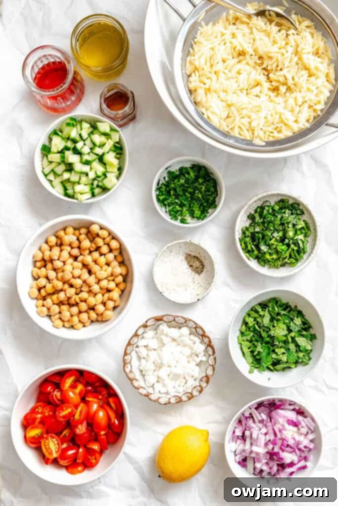Summer Orzo Pasta Salad recipe ingredients laid out, including fresh vegetables, feta, and orzo.