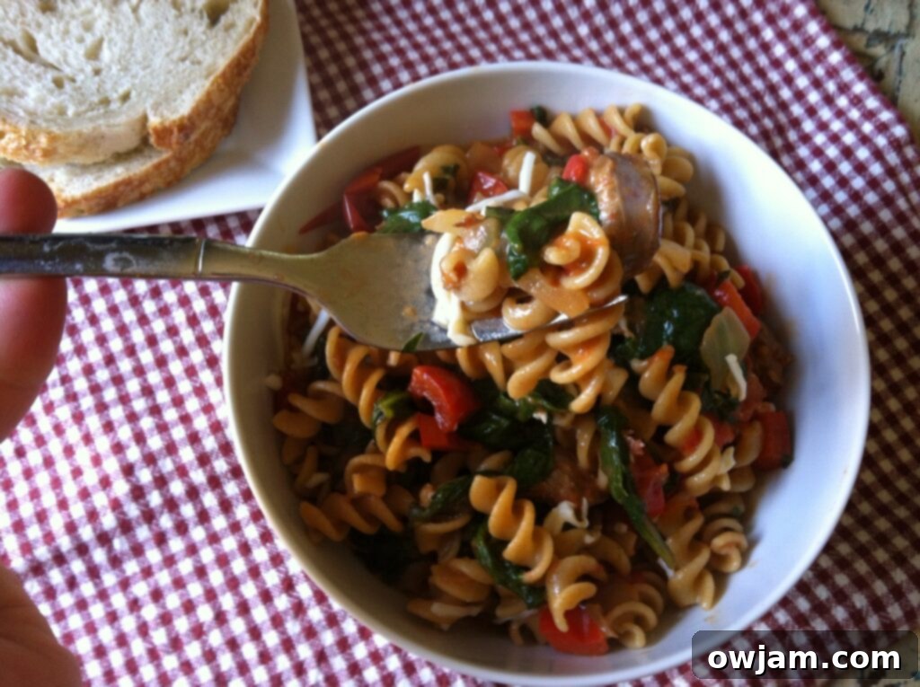 A serving bowl filled with Skillet Sausage and Spinach Pasta, ready to be dished out, highlighting the rich texture and colorful ingredients.