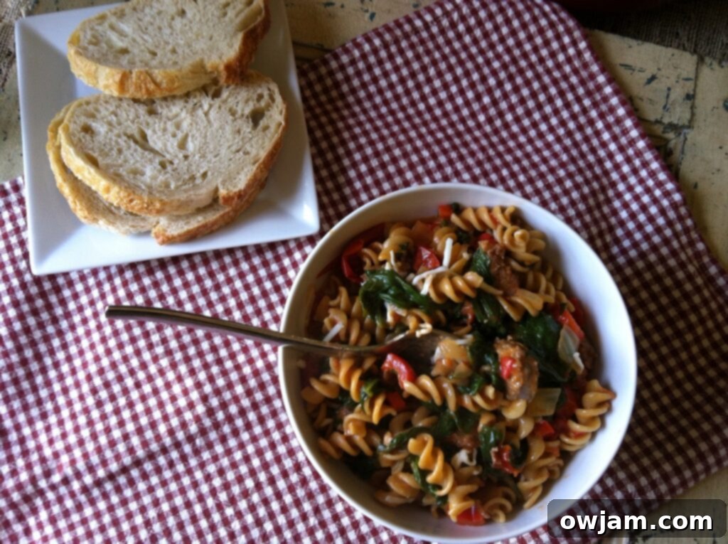 A full plate of Skillet Sausage and Spinach Pasta, showing the complete meal with its rich sauce, sausage, pasta, and vibrant green spinach.