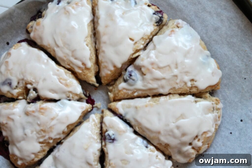 A close-up of a perfectly baked Blueberry-Lemon Yogurt Scone, showcasing its tender crumb and a generous drizzle of lemon glaze, ready to be enjoyed.