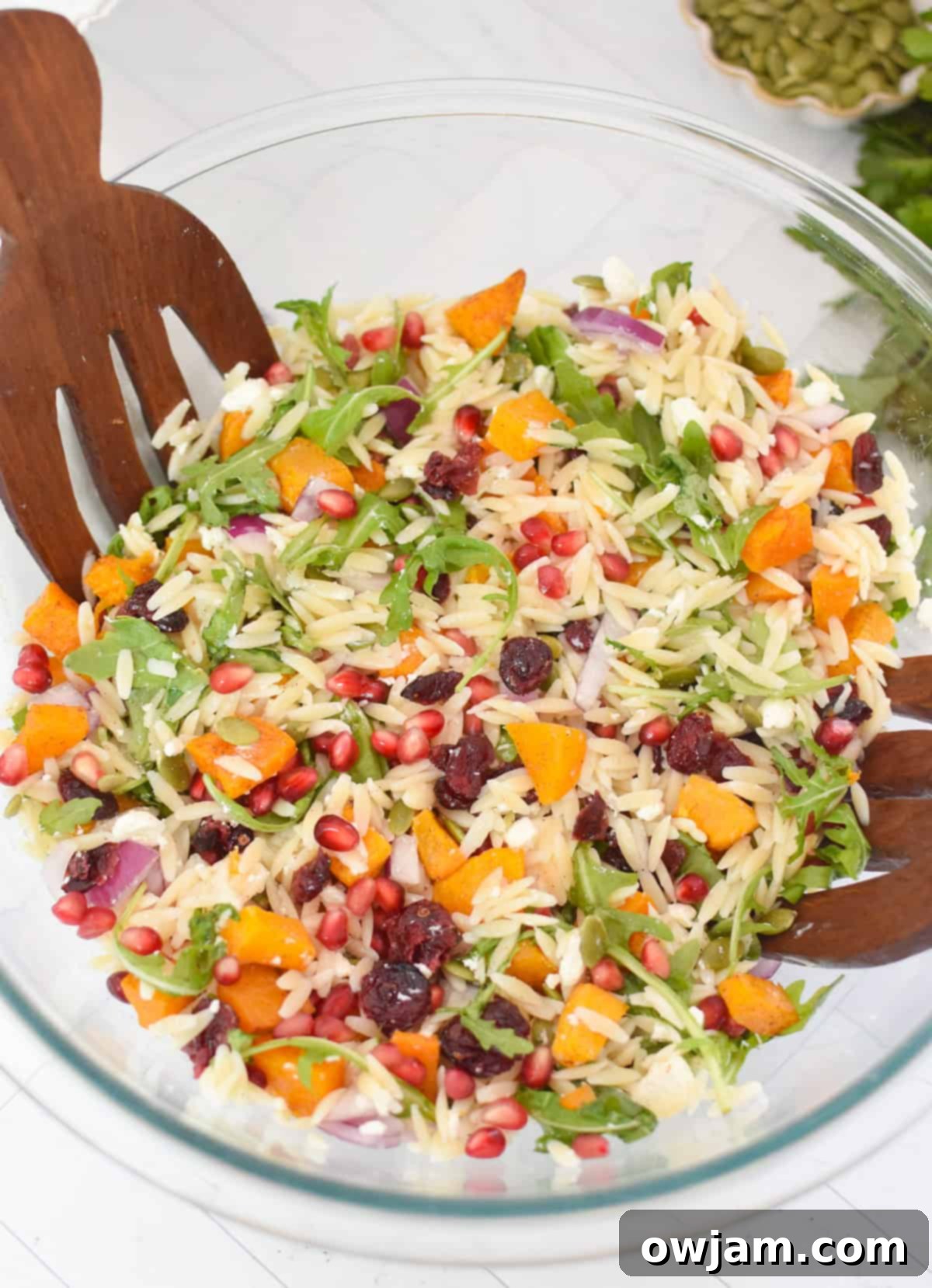 Fall Orzo Pasta Salad with wooden serving forks in a glass bowl
