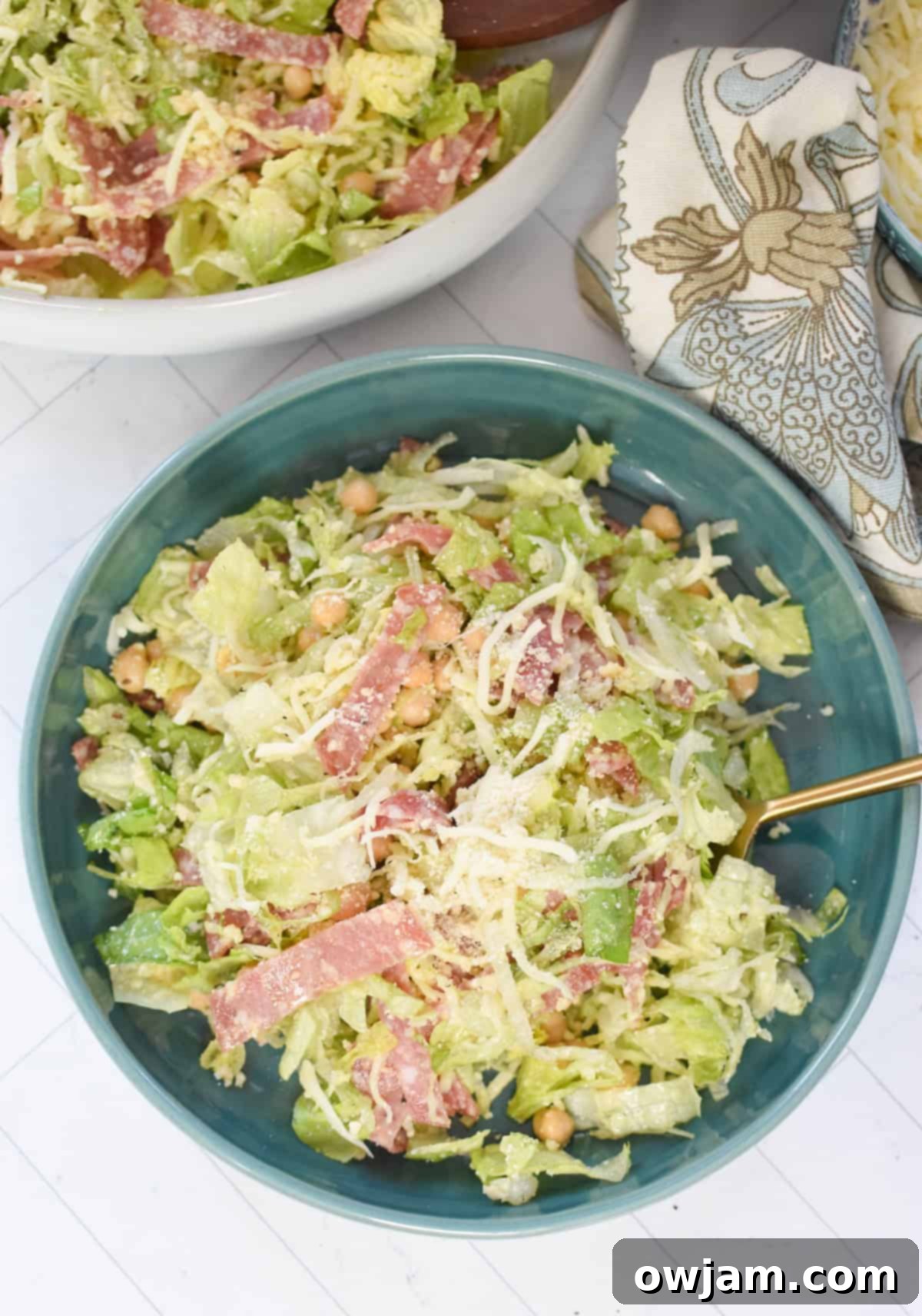 La Scala Style Chopped Salad Made at Home 6 A vibrant Copycat La Scala Chopped Salad served on a teal plate with a golden fork, showcasing the finely chopped ingredients.