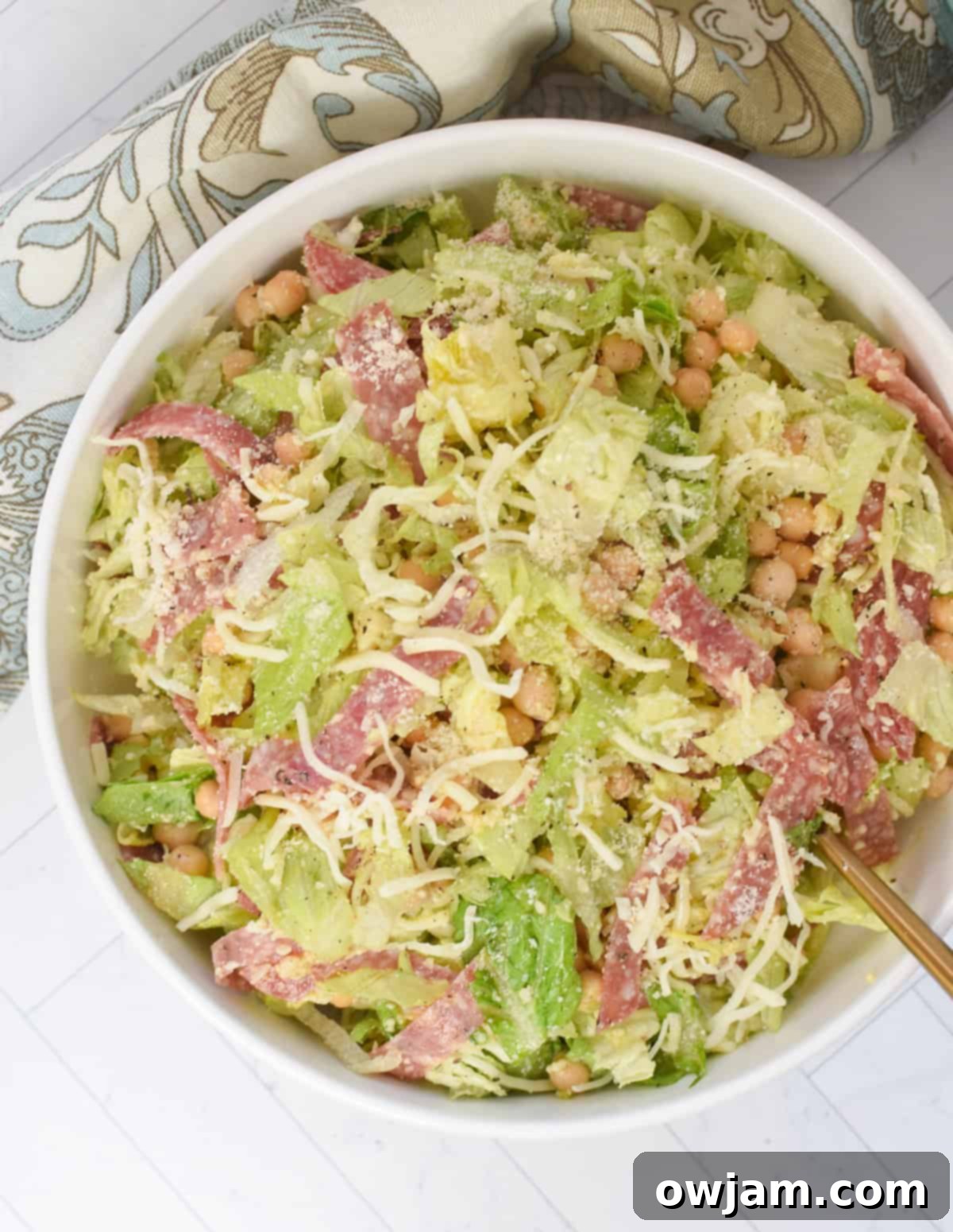 La Scala Style Chopped Salad Made at Home 7 Copycat La Scala Chopped Salad in a white bowl, ready to be served, with a gold fork.