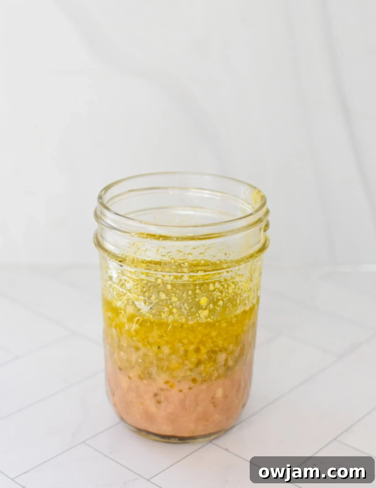 La Scala Style Chopped Salad Made at Home 9 Homemade La Scala salad dressing in a mason jar, showing layers of olive oil, red wine vinegar, and spices.