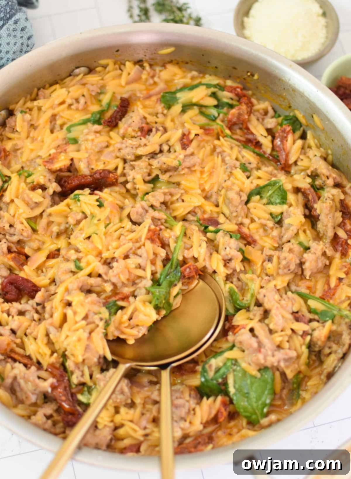 Cozy One Pot Sausage Orzo with a spoon, captured in a skillet ready for serving.