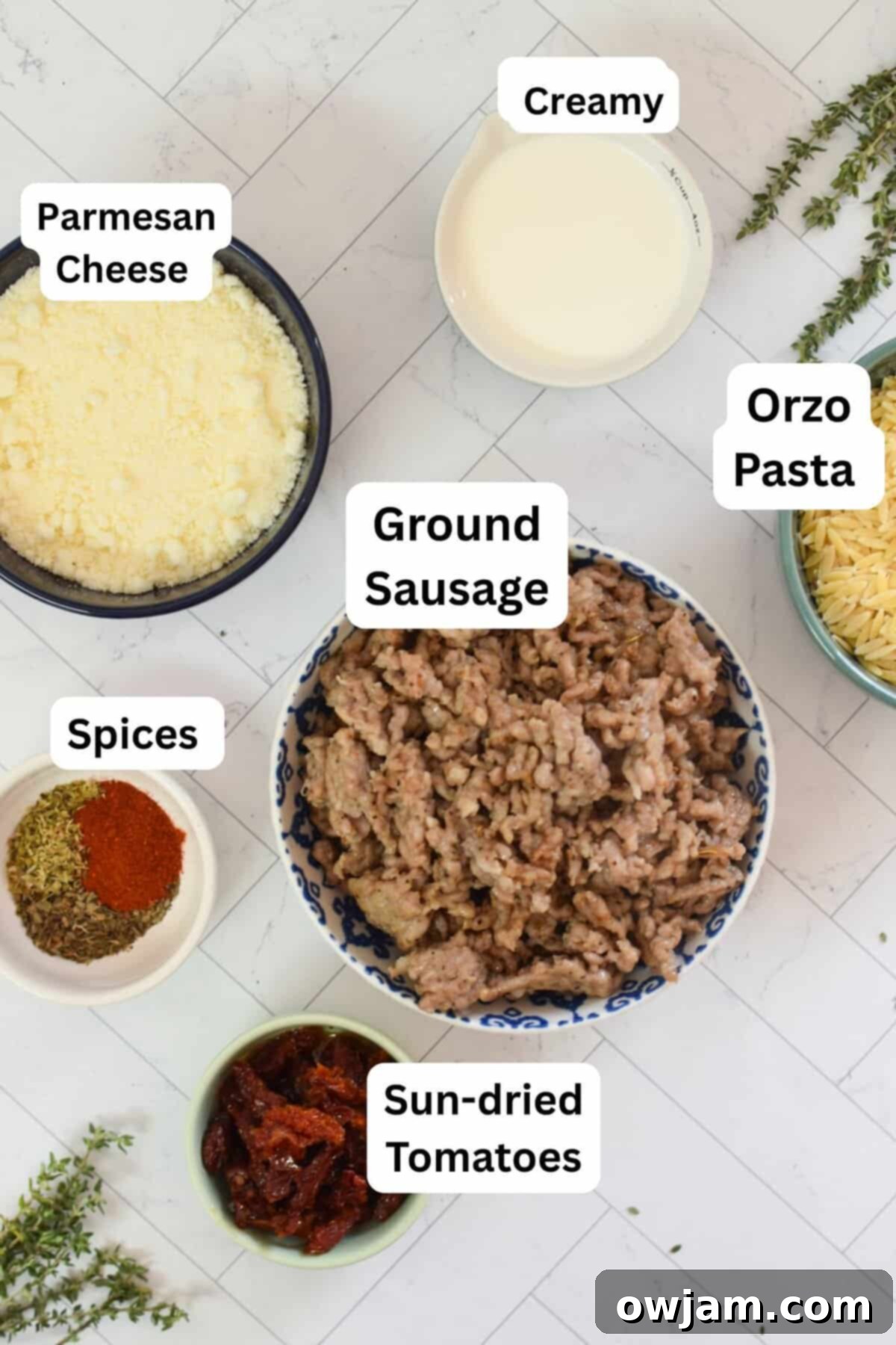 All the fresh ingredients laid out for the One Pot Sausage Orzo recipe: Italian sausage, orzo, garlic, onion, sun-dried tomatoes, spinach, herbs, and Parmesan cheese.