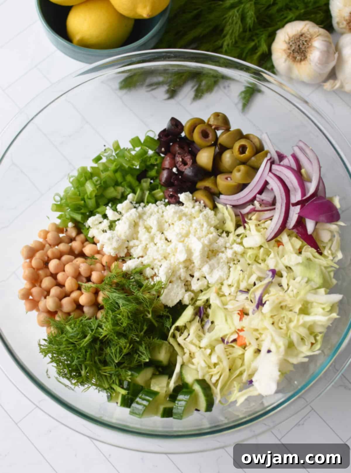 Greek Cabbage Salad ingredients in a large clear bowl